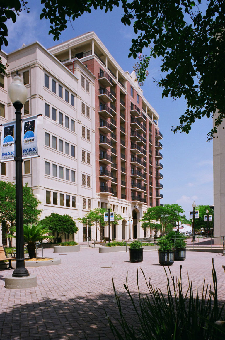 Exterior view of Plaza Tower high-rise condos in Tallahassee, Florida, with Challenger Learning Center and IMAX banners, highlighting properties served by FPAT reserve studies.